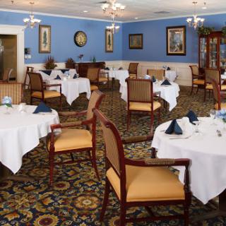 An elegant dining room setup, featuring tables with white tablecloths and a serene blue ambiance.