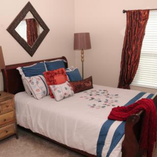 A cozy bedroom with a neatly made bed, decorative pillows, and warm lighting.