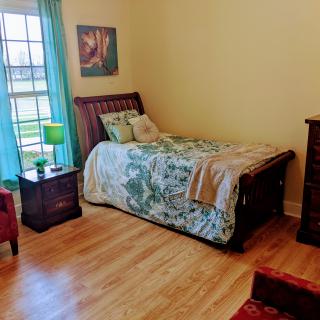 A cozy bedroom with a single bed, nightstand, and hardwood flooring.
