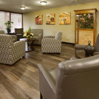 A cozy waiting room with comfortable armchairs, wooden flooring, and decorative art on the walls.