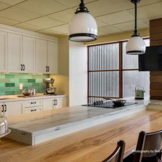 A modern kitchen interior with a large island, pendant lights, and a colorful backsplash.