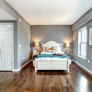 A well-lit bedroom with a comfortable bed, hardwood floors, and stylish decor.