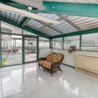 A bright and inviting sunroom featuring a comfortable sofa and large windows that allow natural light to fill the space.