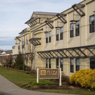 Exterior view of a hotel with a landscaped walkway and entrance sign.