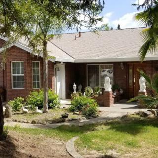 A brick house with a well-maintained front yard featuring statues and greenery.