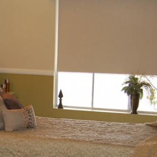 A cozy bedroom with a neatly made bed, pillows, and a decorated window with blinds.