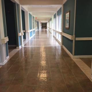 A long, empty hallway with teal walls and shiny floors.