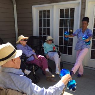 A caregiver engaging with seniors outside on a sunny day.