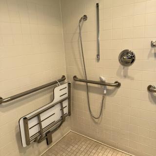 An accessible shower area featuring grab bars and a folding bench for safety and convenience.