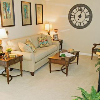 A cozy living room with a beige sofa, wooden coffee tables, and decorative wall art.