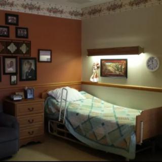 A cozy room with a hospital bed, decorated with pictures and a quilted blanket.