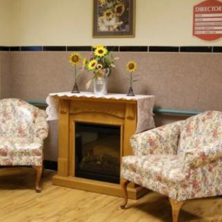 A cozy living room setup featuring a wooden fireplace and floral patterned chairs, adorned with sunflowers.