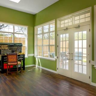 A bright room with green walls and large French doors, featuring a study area with a desk and chair.