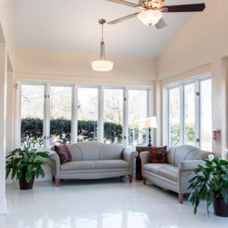 A bright living room with large windows, comfortable sofas, and green plants.