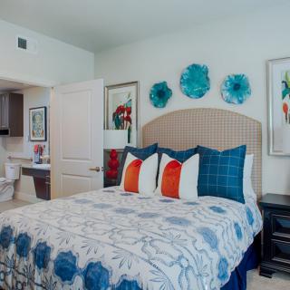 A stylish bedroom with vibrant wall art and colorful pillows.
