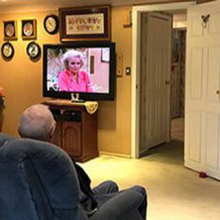An elderly person watching television in a comfortable living room.