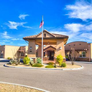 A sunny day view of a building with an entrance, landscaping, and an American flag.