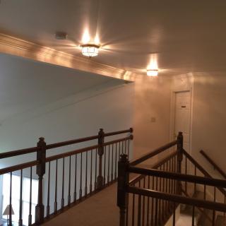 A dimly lit hallway with wooden railings and ceiling lights.