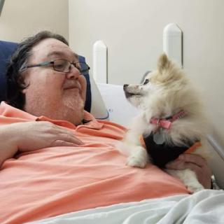 A person enjoying a moment with a Pomeranian dog in a hospital setting.