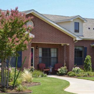 A suburban brick house with a well-maintained garden and landscaping.