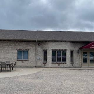 A brick building under a cloudy sky with an entrance and outdoor furniture.