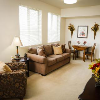 A cozy living room with a sofa, armchair, and dining area.