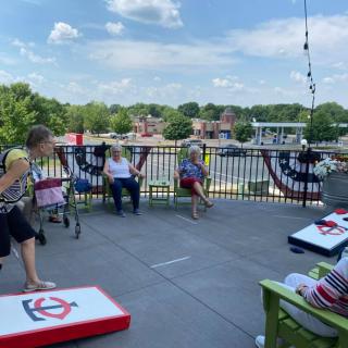 A group of people enjoying a game of cornhole on a sunny patio.