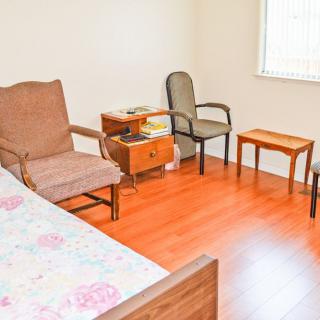 A simple bedroom with chairs, a side table, and a window.