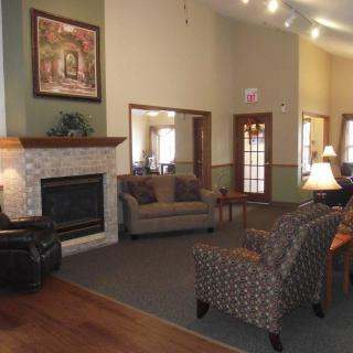 A cozy living room featuring a fireplace, sofa, armchairs, and warm interior design elements.