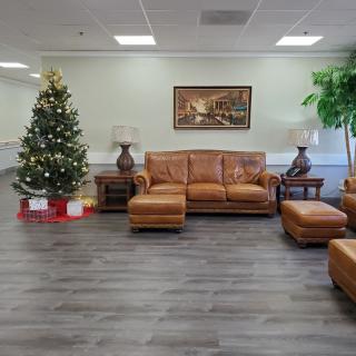 A cozy living room decorated for the holiday season with a Christmas tree and leather furniture.