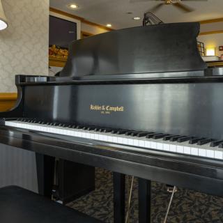 A grand piano with a sleek black finish in a well-lit room.