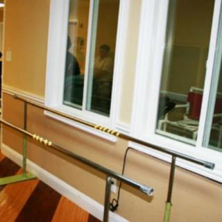 A set of parallel bars used for rehabilitation exercises in an indoor setting.