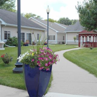 A beautifully landscaped garden area with a pathway, vibrant flowers, and a gazebo in the background.