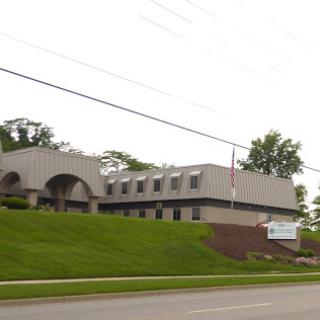 A modern commercial building with a grassy lawn, viewed from the roadside.