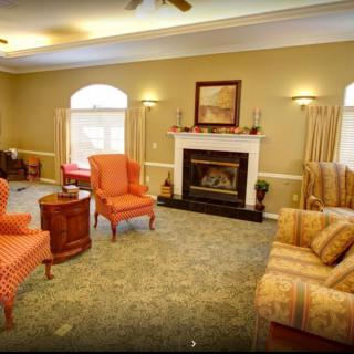 A cozy living room featuring a fireplace, armchairs, and a sofa.