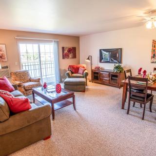 A cozy and well-lit living room featuring a sofa, coffee table, TV, and dining area.