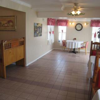 An empty dining area with neatly arranged tables and chairs, featuring a tiled floor and ceiling fan.