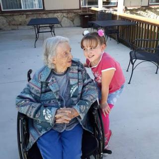 A heartwarming moment shared between a young girl and an elderly woman outdoors.
