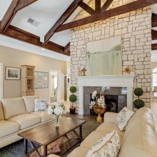 A cozy living room featuring a stone fireplace and wooden beam ceiling.