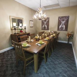 A well-appointed dining room with a long wooden table set for dinner, surrounded by chairs and illuminated by a chandelier.