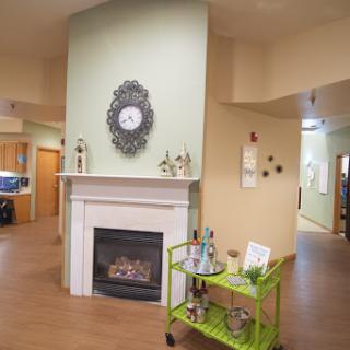 A cozy living space featuring a stylish fireplace, decorative clock, and a vibrant green cart.