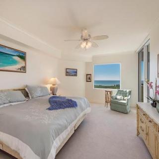 A cozy bedroom with a large bed, ocean-themed decor, and a window offering a stunning ocean view.