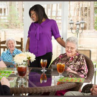 A caregiver spending time with seniors, enjoying a social gathering outdoors.