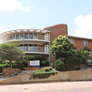 A modern residential building featuring a unique circular design with a landscaped exterior.