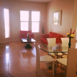 A cozy living room with red sofas, a glass dining table, and wooden flooring.