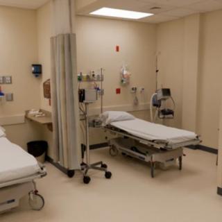 A clean and empty hospital exam room with medical equipment.