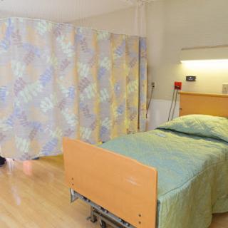 A clean and orderly patient room in a hospital, featuring a bed and privacy curtains.