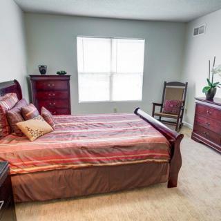 A neatly arranged bedroom with a wooden bed, dresser, and chair.