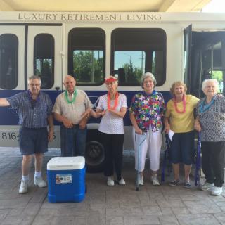 A group of people stand in front of a bus with a cooler nearby.