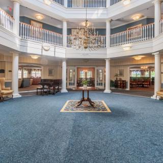 A spacious and elegant lobby with a central chandelier, surrounded by columns and seating areas.